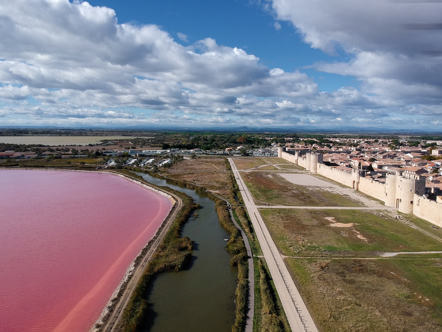 une vue de drone qui résume l'article le lac rose de camargue et les remparts d'Aigues Mortes